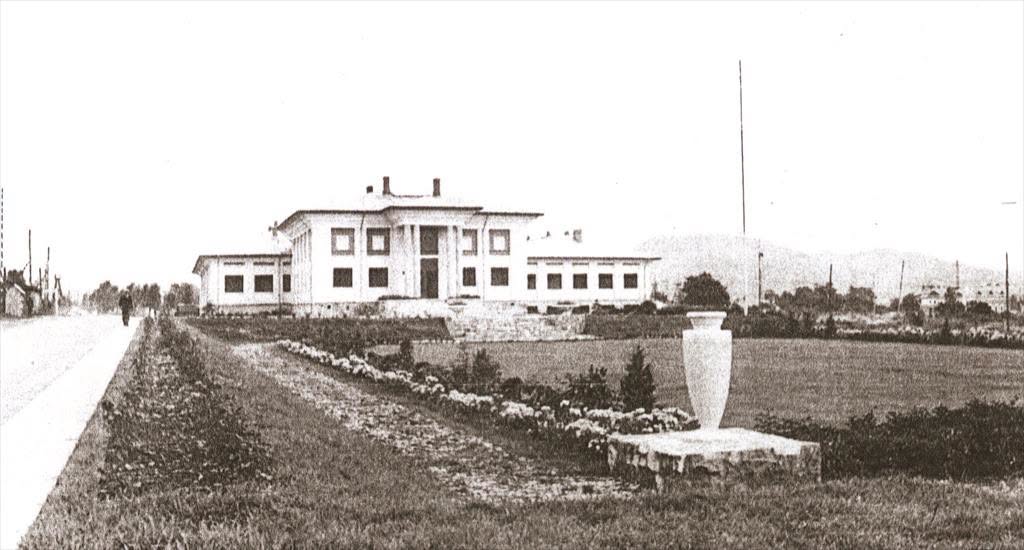 Fotografie postbelică: clădirea cu parcul amenajat și o urnă monumentală pe soclu de piatră